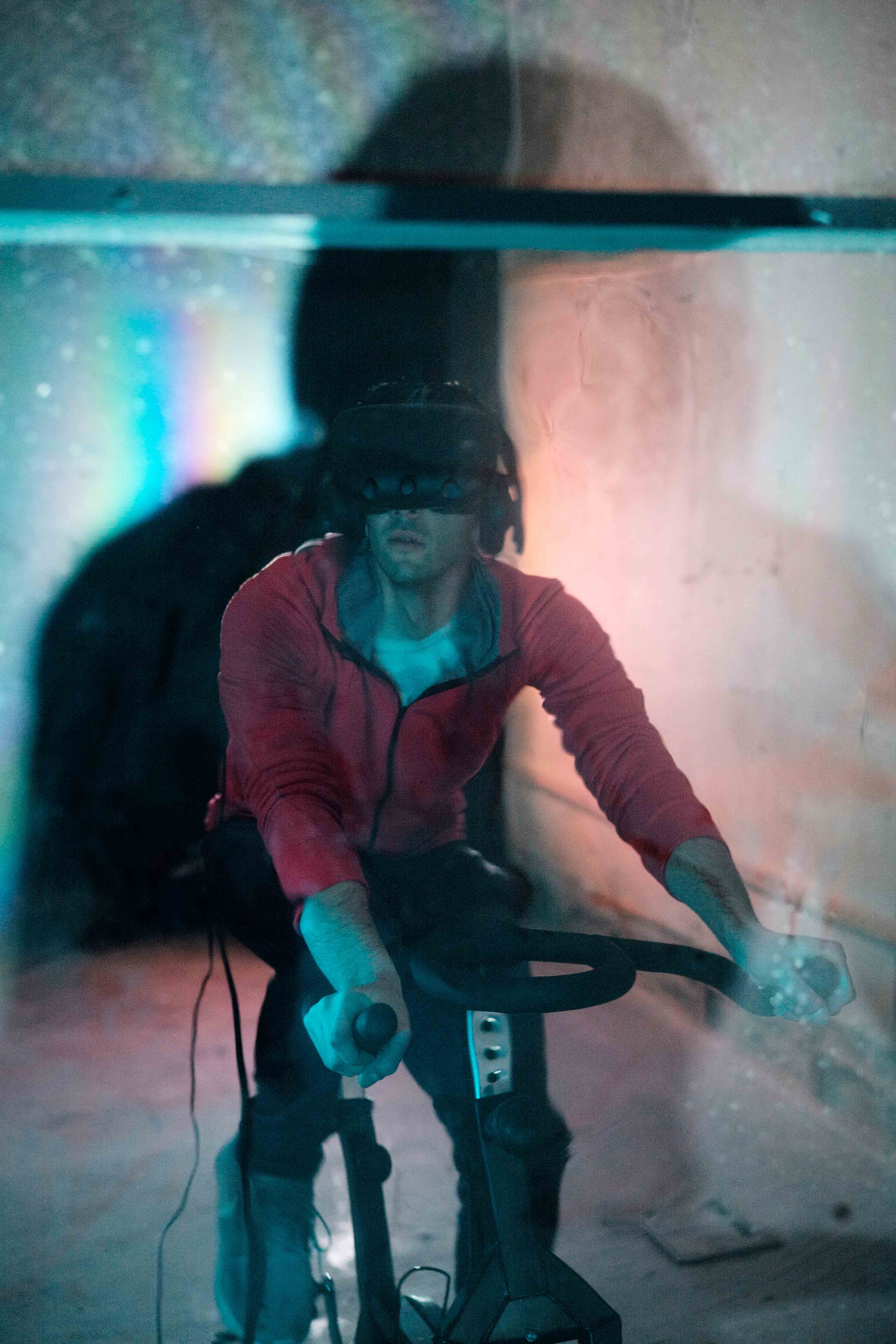 The artist wearing the VR headset whilst using the exercise bike.